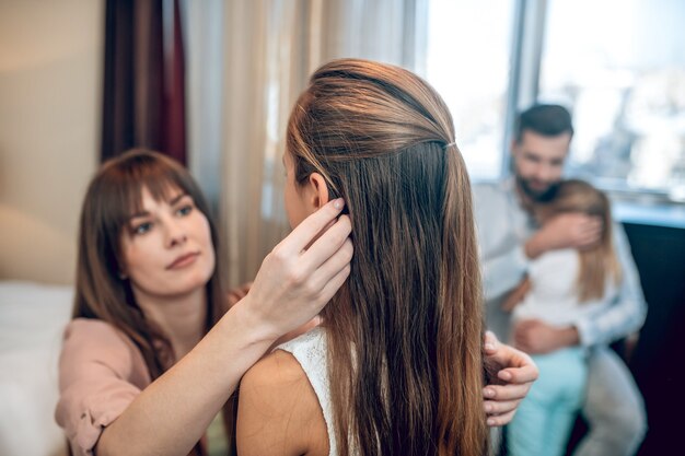 Mamá e hija. Mamá vistiendo a su hija y luciendo involucrada