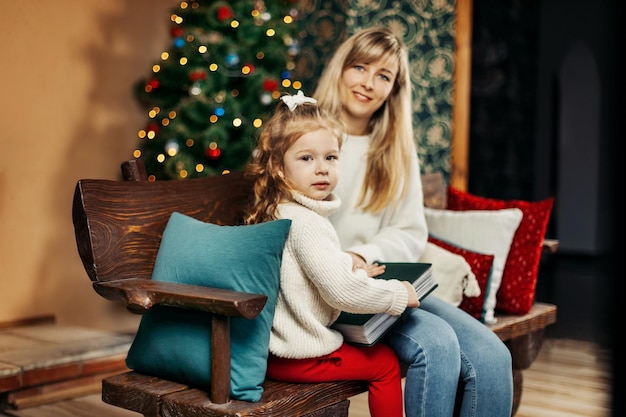 Foto mamá e hija mirando un álbum de fotos familiar en nochebuena