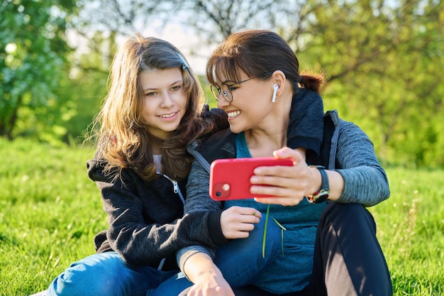 Mamá e hija mirando juntas la pantalla del teléfono inteligente al aire libre