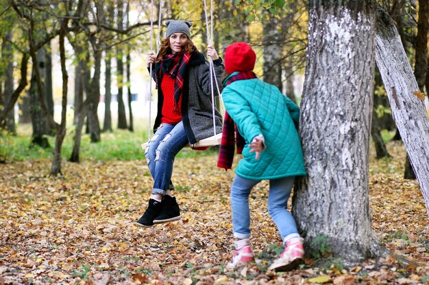 Mamá e hija en un paseo por el parque de otoño durante el otoño del otoño