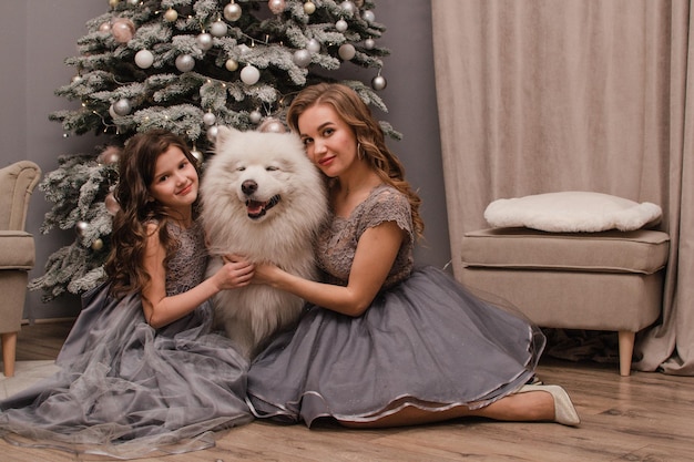 Mamá e hija con un perro Samoyedo Concepto de año nuevo