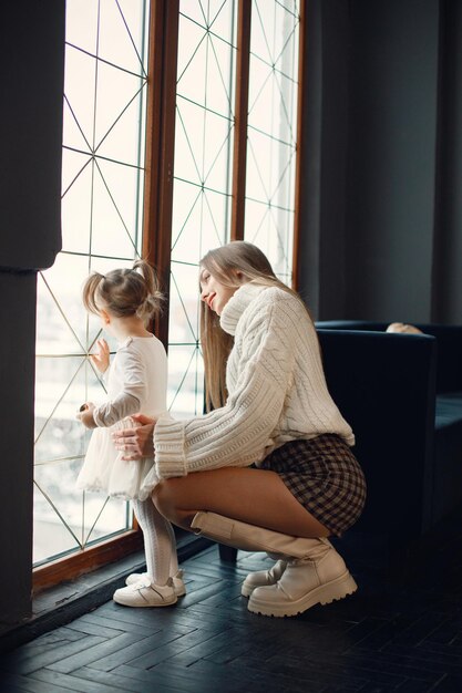 Mamá e hija de pie y mirando por una ventana grande