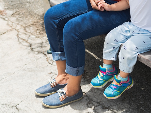 Mamá e hija piernas sentado en la silla en el parque. Concepto de familia feliz.