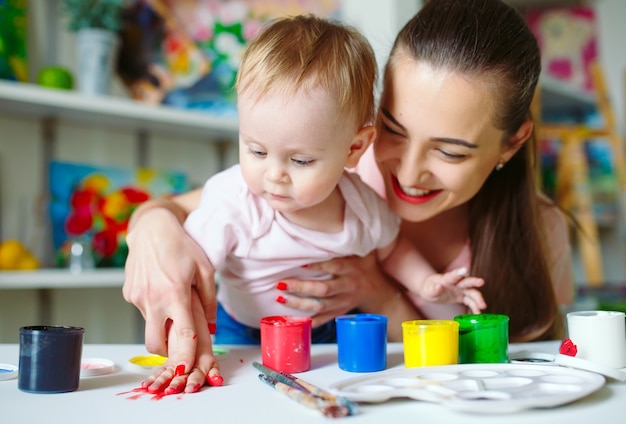 Foto mamá e hija pintan sobre lienzo en la escuela de dibujo.