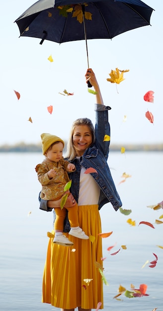 Foto mamá e hija en la playa con sombrilla con hojas.