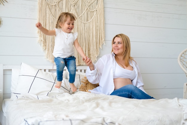 Foto mamá e hija saltan y se divierten en la cama en el dormitorio.