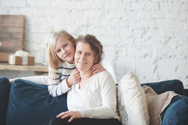 Mamá e hija sentadas en el sofá del apartamento