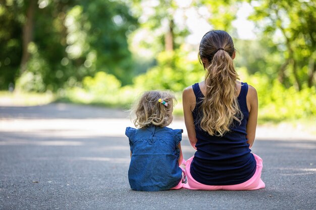 Mamá e hija se sientan juntas en un parque