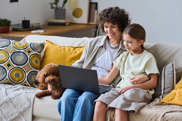 Mamá e hija usando laptop en casa