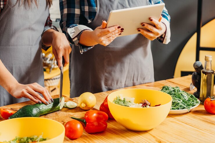 Foto mamá e hija usando la tableta cuando cocinan en la cocina