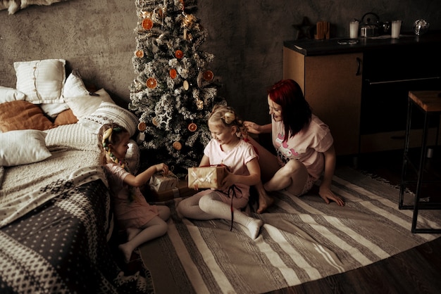 Mamá e hijas cerca del árbol de Navidad. Año nuevo