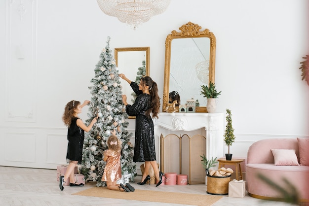 Mamá e hijas decoran el árbol de Navidad para la celebración del Año Nuevo.