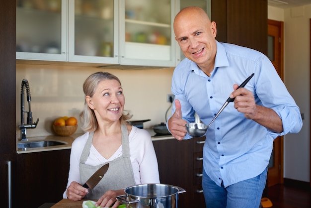 Mamá e hijo adulto en la cocina preparando comida juntos