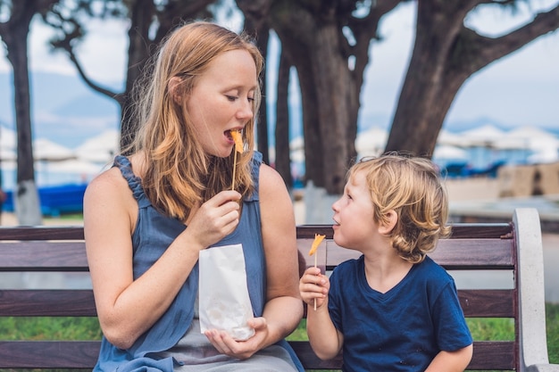 Mamá e hijo comen batatas fritas en el parque