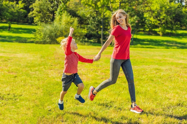 Mamá e hijo corren sobre la hierba verde. Familia feliz en el parque.