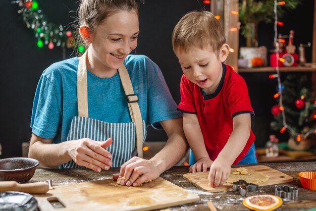 Mamá e hijo dan forma a la masa para hornear pan de jengibre navideño casero