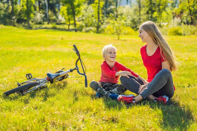 Mamá e hijo descansan en el césped después de andar en bicicleta.