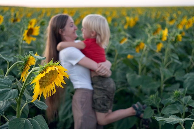 Mamá e hijo se divierten en el campo de girasoles. Familia feliz.