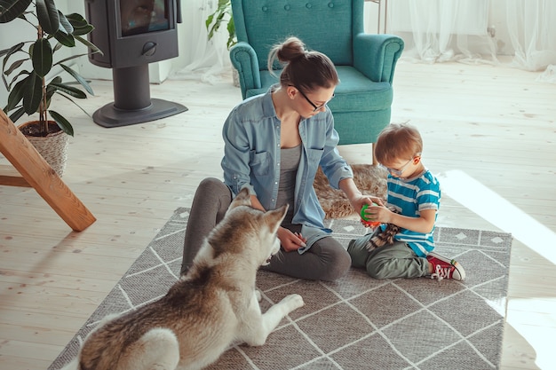 Mamá e hijo se divierten y juegan con el perro en casa.