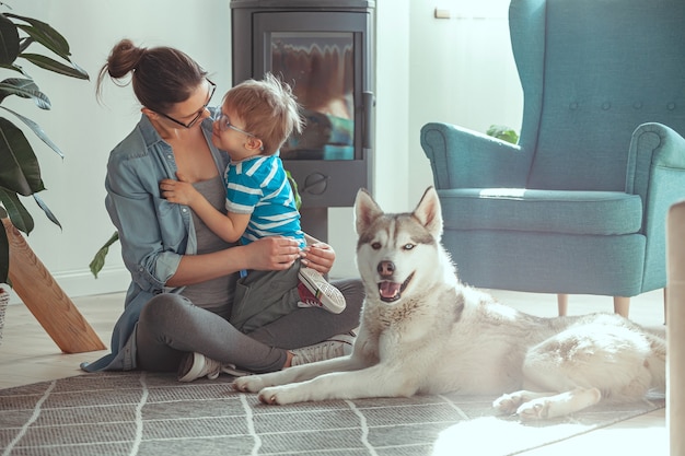 Mamá e hijo se divierten y juegan con el perro en casa.