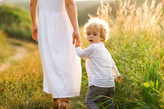 Mamá e hijo están caminando en la naturaleza tomados de la mano