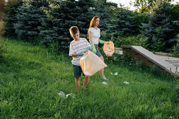 Mamá e hijo están limpiando basura en el parque al atardecer Reciclaje de residuos de cuidado ambiental