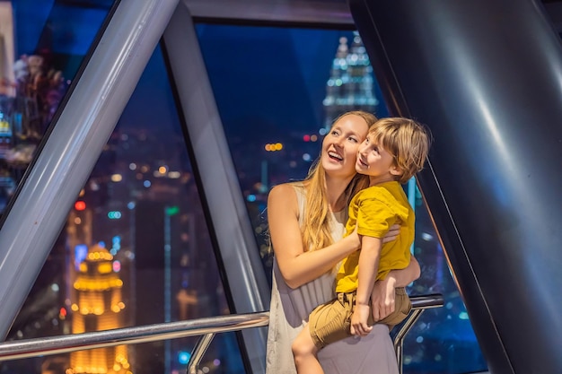 Mamá e hijo están mirando el paisaje urbano de Kuala Lumpur Vista panorámica del horizonte de la ciudad de Kuala Lumpur por la noche en el edificio de rascacielos al atardecer en Malasia Concepto de viaje con niños