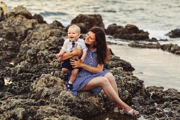 Mamá e hijo. La familia pasea por la playa pedregosa junto al mar.