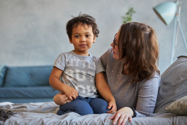 Mamá e hijo feliz en un elegante apartamento en la cama