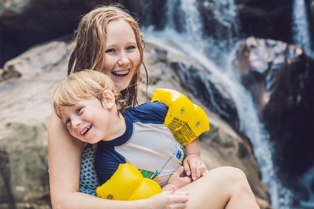 Mamá e hijo en el fondo de la cascada. Viajar con el concepto de niños.