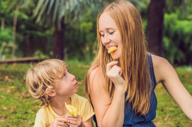 Mamá e hijo hicieron un picnic en el parque. Coma frutas saludables: mango, piña y melón. Los niños comen alimentos saludables.