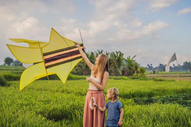 Mamá e hijo lanzan una cometa en un campo de arroz en ubud bali island indonesia