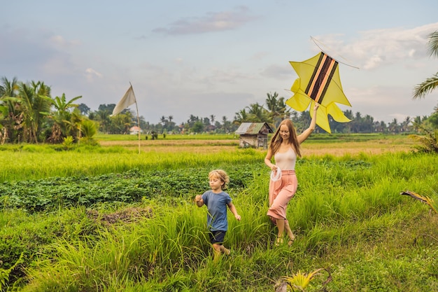 Mamá e hijo lanzan una cometa en un campo de arroz en ubud bali island indonesia