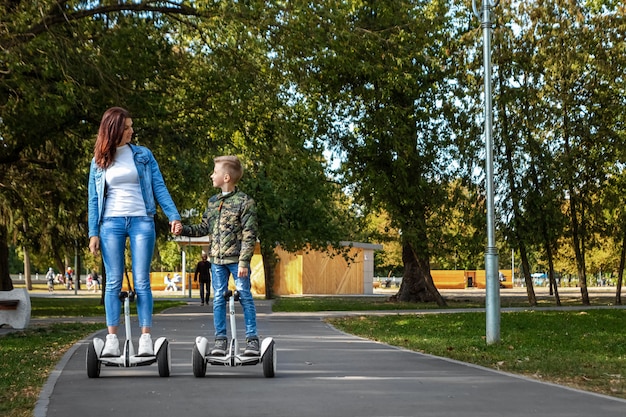 Mamá e hijo montan un hoverboard en el parque