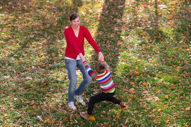 Mamá e hijo pequeño están caminando en el parque de otoño