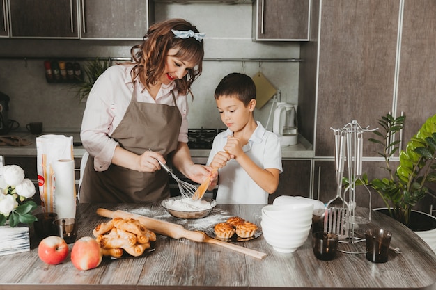 Mamá e hijo preparan un pastel de cumpleaños en la cocina para el Día de la Madre, una serie de imágenes del estilo de vida cotidiano en el interior de la vida real.