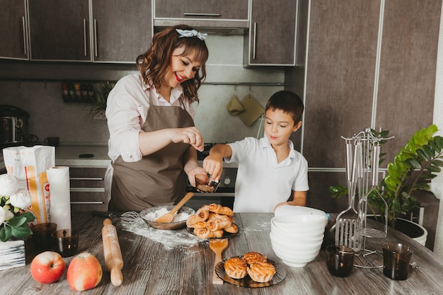 Mamá e hijo preparan un pastel de cumpleaños en la cocina para el Día de la Madre, una serie de imágenes del estilo de vida cotidiano en el interior de la vida real.