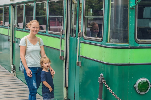 Mamá e hijo van a ir en un tranvía viejo. Viajar con niños en concepto de Hong Kong.