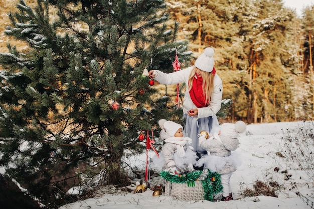 Mamá e hijos en el árbol de Navidad en la calle lo decoran