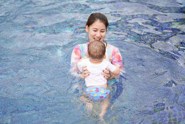 Foto mamá le enseña a un niño a nadar en la piscina tan feliz y divertido