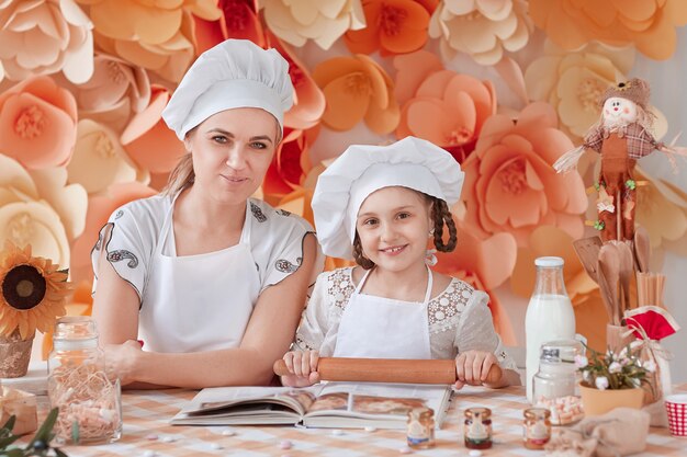 Mamá enseña a su pequeña hija a extender la masa. el concepto de paternidad