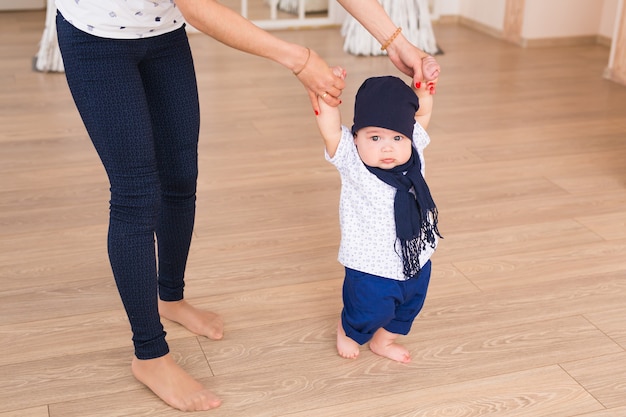 Mamá enseñando los primeros pasos de bebé de su hijo en el interior.