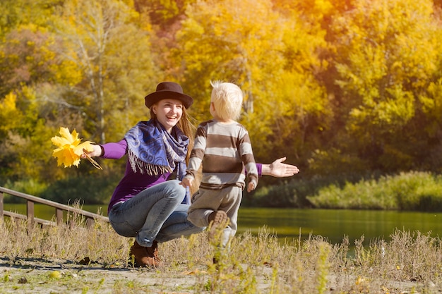 Mama erwischt laufenden Sohn Autumn an einem sonnigen Tag am Flussufer