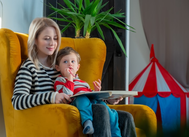 Mama erzählt ihrem Sohn eine Geschichte, während sie zu Hause im Sessel sitzt