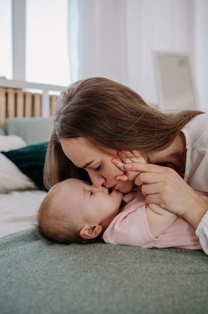 Mamá está acostada en la cama besando a su hija