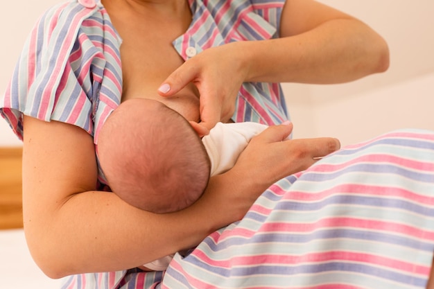 La mamá está amamantando a su bebé recién nacido en la cama.