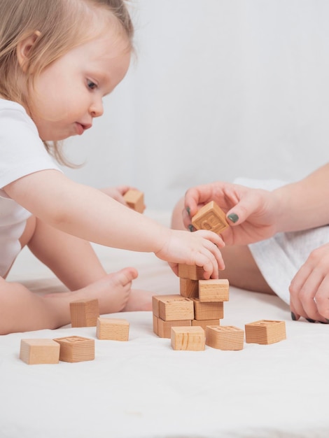 Mamá está jugando con un niño construyendo una casa con cubos de madera ecológicos cerrados El concepto de desarrollo infantil temprano a través de juegos Ambiente acogedor y hogareño Día de la Madre Día del Niño