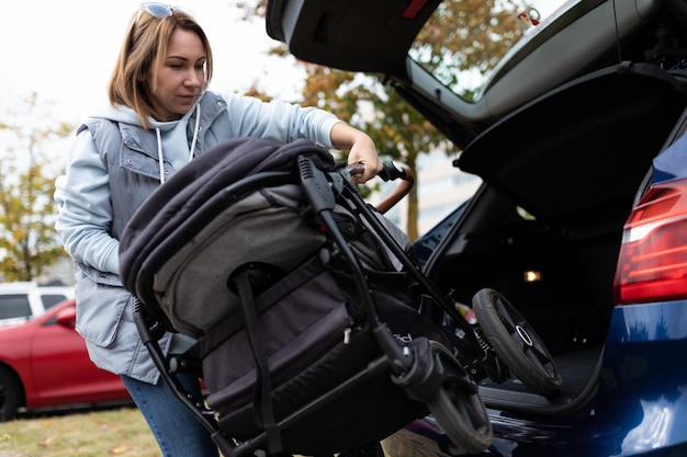 Foto mama fahrer legt kinderwagen in den kofferraum