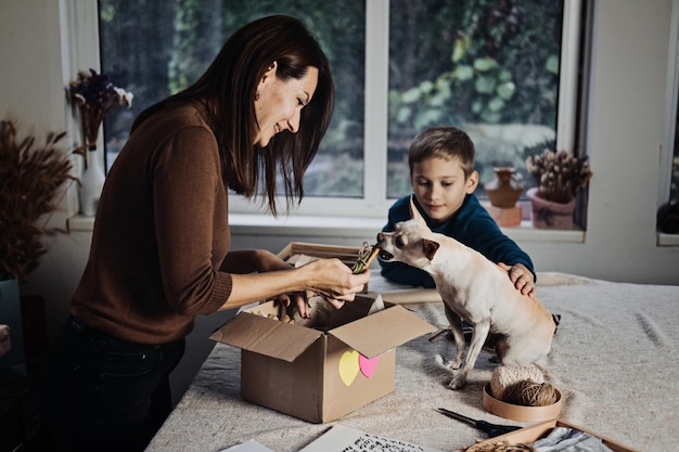 Mamá de familia feliz y niño poniendo hueso en caja de suscripción para mascotas para perros chihuahua y