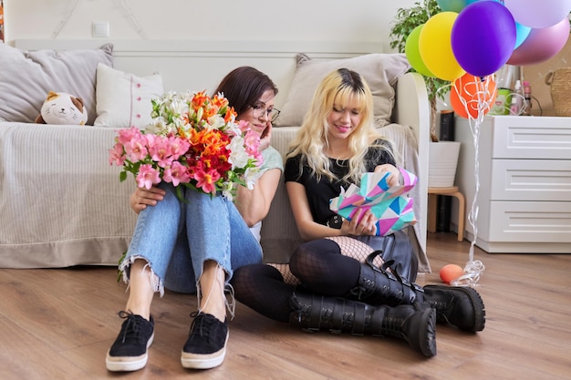 Mamá felicitando a su hija con ramo de flores y caja de regalo sorpresa